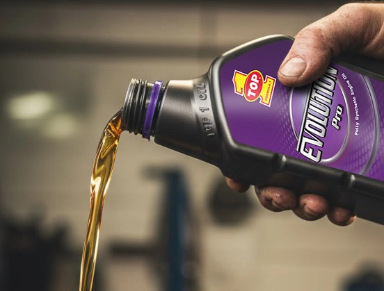Oil viscosity explained as engine oil is poured from a TOP 1 Evolution Pro bottle in a garage